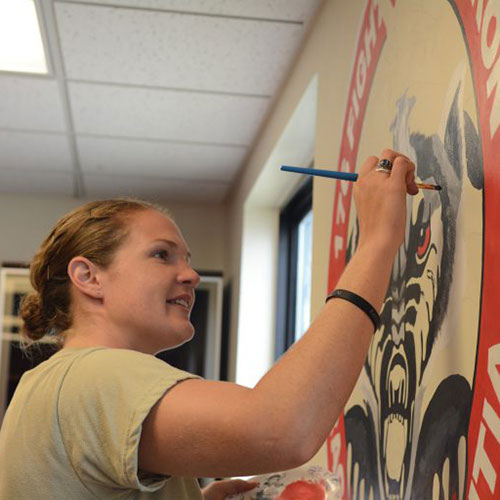 115th Fighter Wing Airman Seniuk painting a logo on a wall